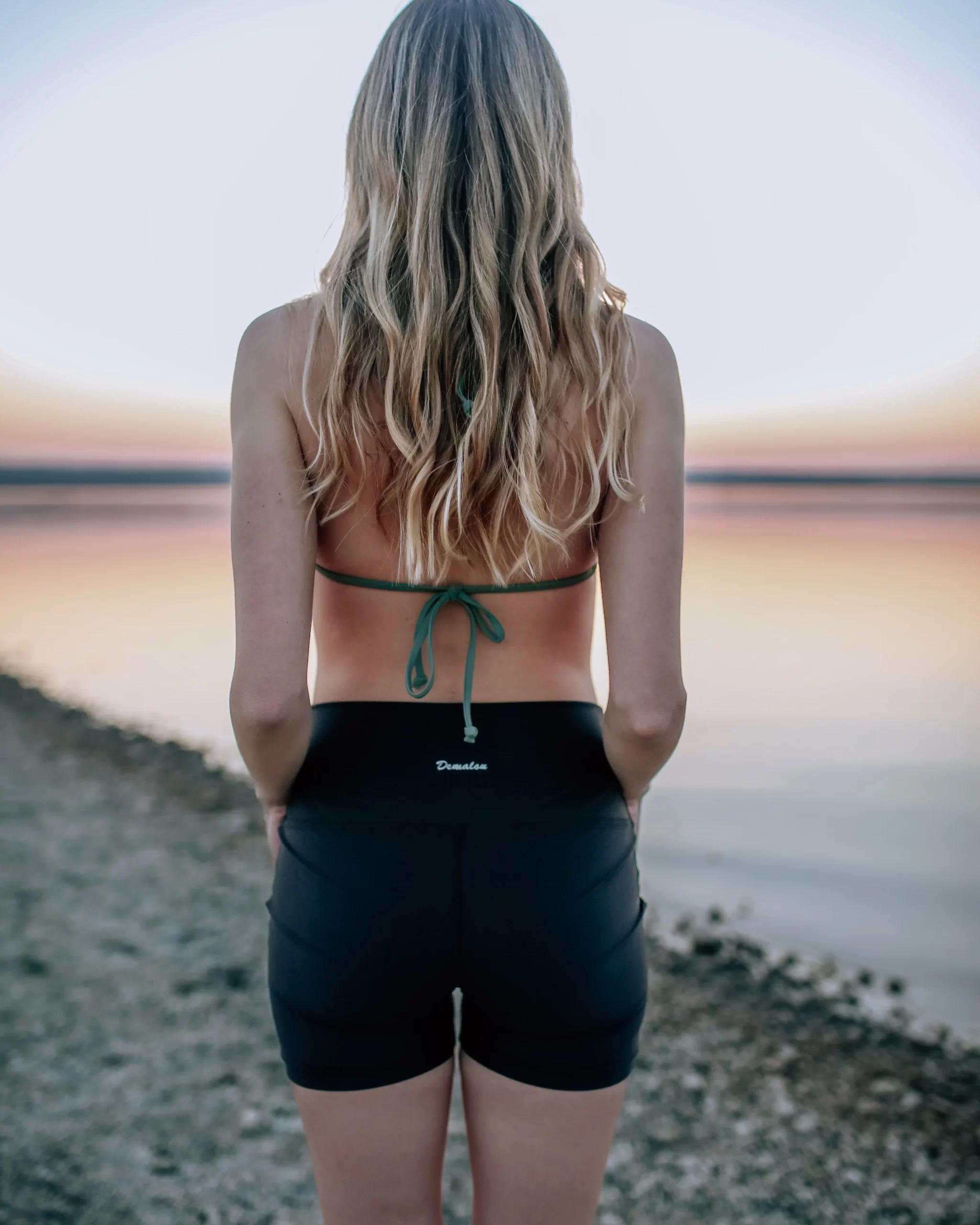 Frau in Bikinioberteil mit Schwimmshorts aus nachhaltigem Material, speziell geeignet zum Surfen